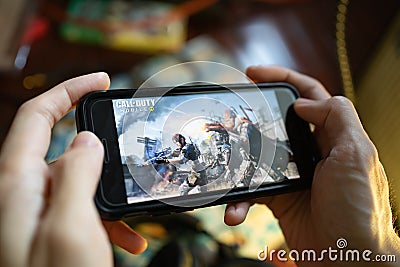A man playing Call of Duty Mobile game on iPhone 7. Editorial Stock Photo