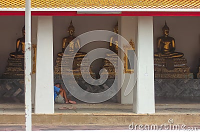 Bangkok, Thailand - April 29, 2014. Man resting and praying in front of Golden Buddha sculptures at Wat Pho, Bangkok Editorial Stock Photo