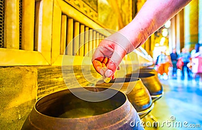 Dropping coin in bronze bowl in Wat Pho temple, Bangkok, Thailand Editorial Stock Photo