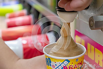 BANGKOK, THAILAND - DECEMBER 18: Slurpee machine fills up a paper cup with Coca-Cola flavored Slurpee in 7-Eleven on Petchkasem 69 Editorial Stock Photo