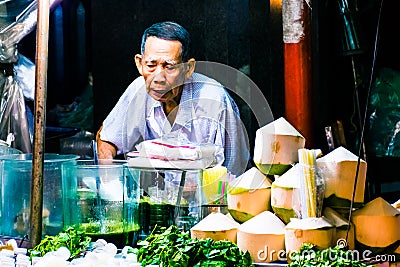 Bangkok, Thailand, January 12 2018: Trader cutting the coconut for coconut water in China Town market of Bangkok Editorial Stock Photo