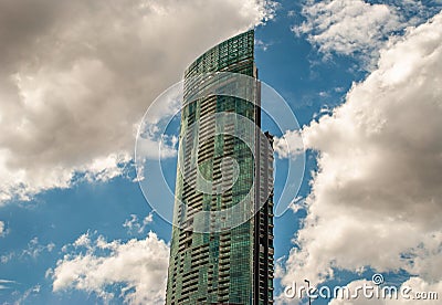 Angular geometric mirror cladding on a modern building with repeating structure and reflected sky and clouds Editorial Stock Photo