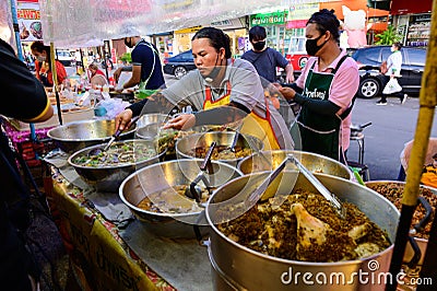 Bangkok, Thailand - June 23, 2020 : Unidentified vendor scoop food into plastic bag for customer Editorial Stock Photo