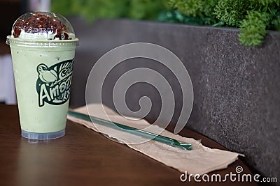 Bangkok, Thailand - March 22, 2020: Milk green tea frappe topping with red beans on wood table at Cafe Amazon are found in every Editorial Stock Photo