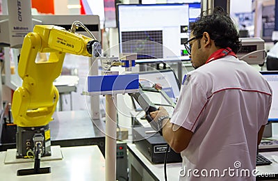 Worker control robot arm to loading and unloading workpiece Editorial Stock Photo