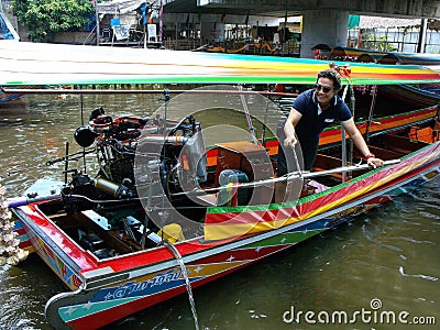 A man drives a boat with a powerful motor at the Taling Chan Floating Market in Bangkok Editorial Stock Photo