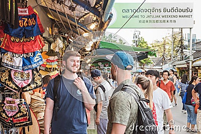 Bangkok: travelers stand by counter with Muay Thai boxers with signboard saying `Welcome to Jatujak Weekend Market` Editorial Stock Photo