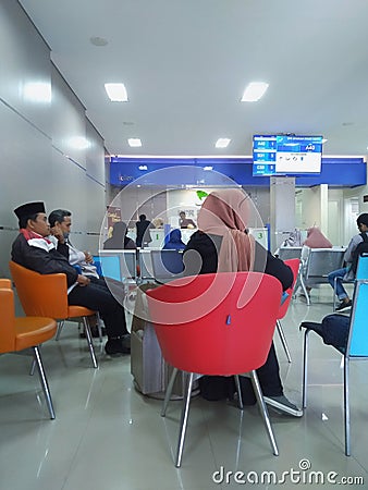 Bank customers sitting, waiting for financial transactions at Bank Dinar.. Editorial Stock Photo