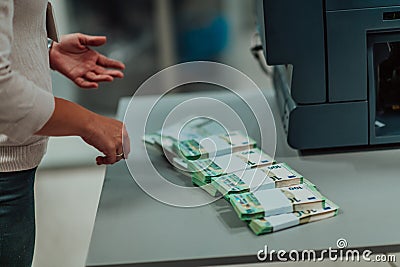 Bank employees using money counting machine while sorting and counting paper banknotes inside bank vault. Large amounts Stock Photo