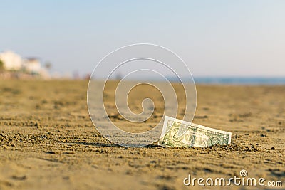 Banknote of value of one dollar in the the sand on the beach. Concept of cheap travel and vacation. Stock Photo