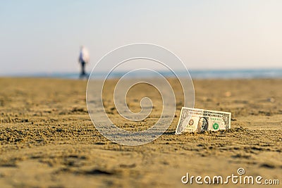 Banknote of value of one dollar in the the sand on the beach. Concept of cheap travel and vacation. Stock Photo