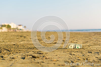 Banknote of value of one dollar in the the sand on the beach. Concept of cheap travel and vacation. Stock Photo