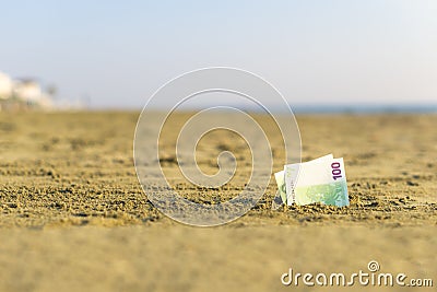 Banknote of value of one hundred euro in the the sand on the beach. Concept of cheap travel and vacation. Stock Photo