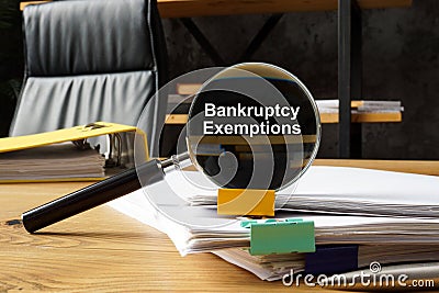 Bankruptcy exemptions concept. A magnifying glass lies on a stack of papers. Stock Photo