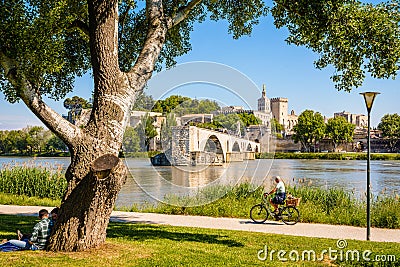 The banks of the Rhone on a sunny day, opposite the Saint-Benezet bridge and the Papal palace in Avignon, France Editorial Stock Photo