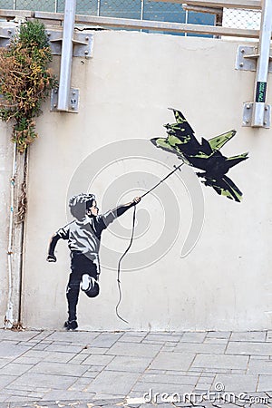 Banksy street art graffiti boy with fighter aircraft kite in Tel Aviv, Israel Editorial Stock Photo