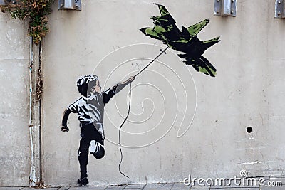 Banksy street art graffiti boy with fighter aircraft kite in Tel Aviv, Israel Editorial Stock Photo