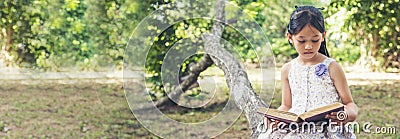 Banner Asian Girl holding book reading at green park in nature garden. Panorama Young todler girl relaxation read book. Happy Stock Photo