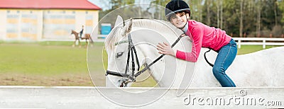 A sweet girl riding a white horse, an athlete engaged in equestrian sports, a girl hugs and kisses a horse. Stock Photo