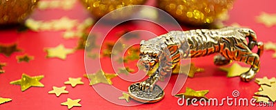 Banner with bronze figure of a tiger with coin - symbol of the Chinese new year 2022 on a red background with golden stars, balls Stock Photo