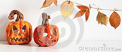 Banner with Ceramic Jack Lanterns and autumn leaves garland on table wall background Stock Photo