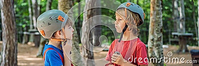 BANNER, LONG FORMAT Friends on the ropes course. Young people in safety equipment are obstacles on the road rope Stock Photo