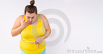 Banner,long format. A plump woman with a surprised face measures the size of her belly with a centimeter. Excess weight Stock Photo