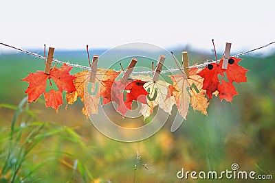 Banner with the name and the word autumn carved on red maple leaves hanging on clothespins and rope in the autumn Sunny Park Stock Photo