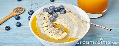 Banner with oatmeal, bananas, blueberries, chia seeds, mango jam on blue wooden background. Side view. Healthy breakfast Stock Photo