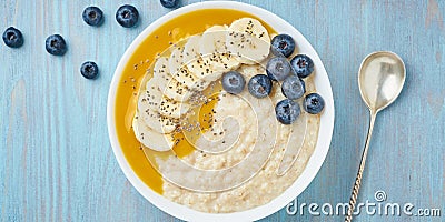 Banner with oatmeal, bananas, blueberries, chia seeds, mango jam on blue wooden background. Top view. Healthy breakfast Stock Photo