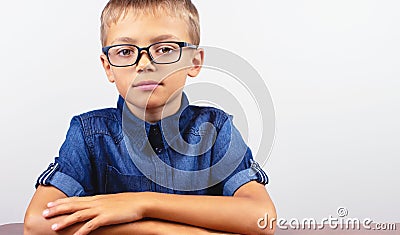 Banner Schoolboy in a blue shirt sitting at the table. Boy with glasses on white background Concept back to school Stock Photo