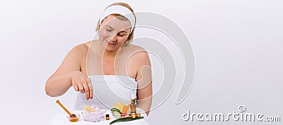 Banner. A senior woman at home, wrapped in a white towel prepares a face and body mask from natural products. Homemade Stock Photo