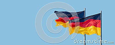 Banner with two national black red yellow flags of Germany at blue sky solid background with copy space, details, closeup. Concept Stock Photo