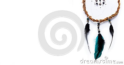 A unique mystical dream catcher made of willow vines, white threads, beads, colored feathers, placed horizontally. Stock Photo