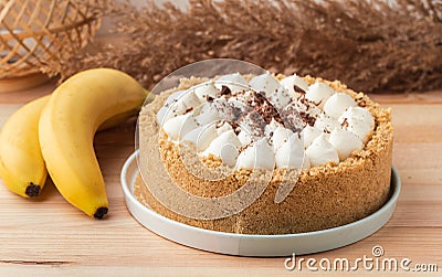 Banoffee cake with banana and caramel sauce filling sprinkled with grated dark chocolate on the wooden rustic background. English Stock Photo