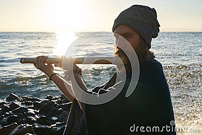 Bansuri player playing music in sunshine at sea shore. Stock Photo