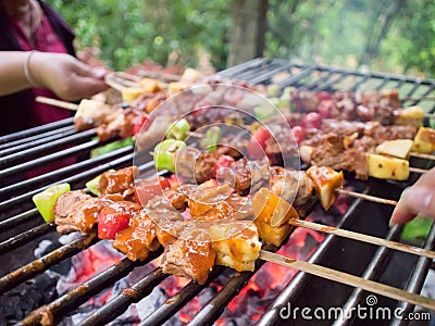 Bar-B-Q or BBQ with kebab cooking. coal grill of pock meat skewers with pineapple and green pepper. barbecuing dinner. Stock Photo