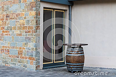 Bar table in the form of a wooden barrel in front of a glass door Stock Photo