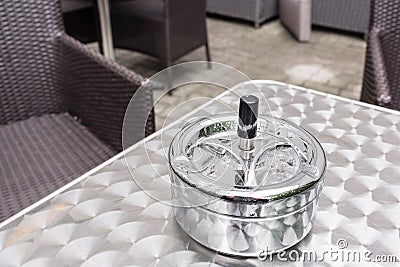 A bar terrace at a rainy day, ashtray on a metal table. Cafe table and chairs, Austria. Stock Photo