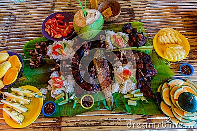 Barbecue of chicken, pork and fish is served on bamboo leaves with vegetables and fruits. Filipino cuisine Stock Photo