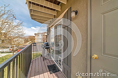 Barbecue grill on small balcony with roof overhang and huge window with shutters Stock Photo