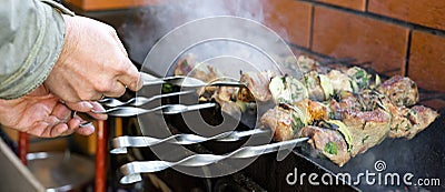 Barbecue. The hands of an unidentified caucasian man is turning over skewers. Selective focus. Stock Photo