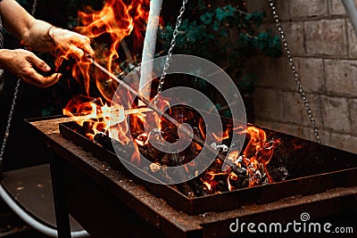 barbecue man fixes burning firewood in the barbecue in the yard Stock Photo