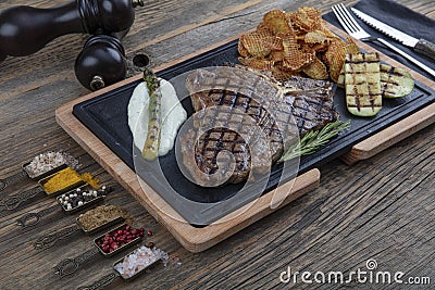 Barbecued t-bone steak seasoned with fresh herbs and marinade served with a cutting board in a steakhouse. Delicious restaurant Stock Photo