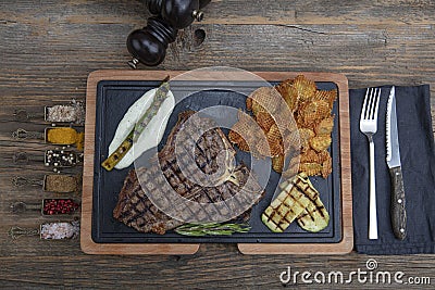 Barbecued t-bone steak seasoned with fresh herbs and marinade served with a cutting board in a steakhouse. Delicious restaurant Stock Photo