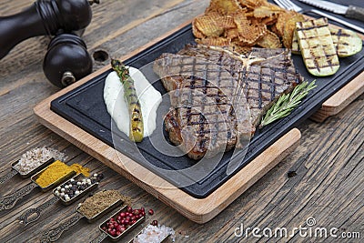 Barbecued t-bone steak seasoned with fresh herbs and marinade served with a cutting board in a steakhouse. Delicious restaurant Stock Photo