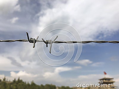 Barbed wire against blue sky and defocused building Stock Photo
