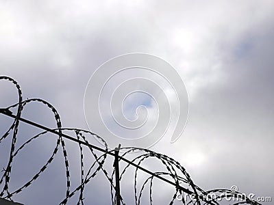 Barbed wire on the background the gray sky. Prison concept, rescue, refugee, space for text Stock Photo