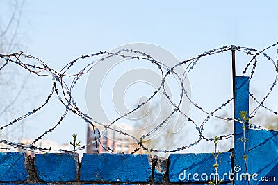 Barbed wire on a blurred background of a fragment of residential buildings. Concept of isolation. Selective focus Stock Photo