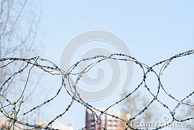 Barbed wire on a blurred background of a fragment of residential buildings. Concept of isolation. Selective focus Stock Photo